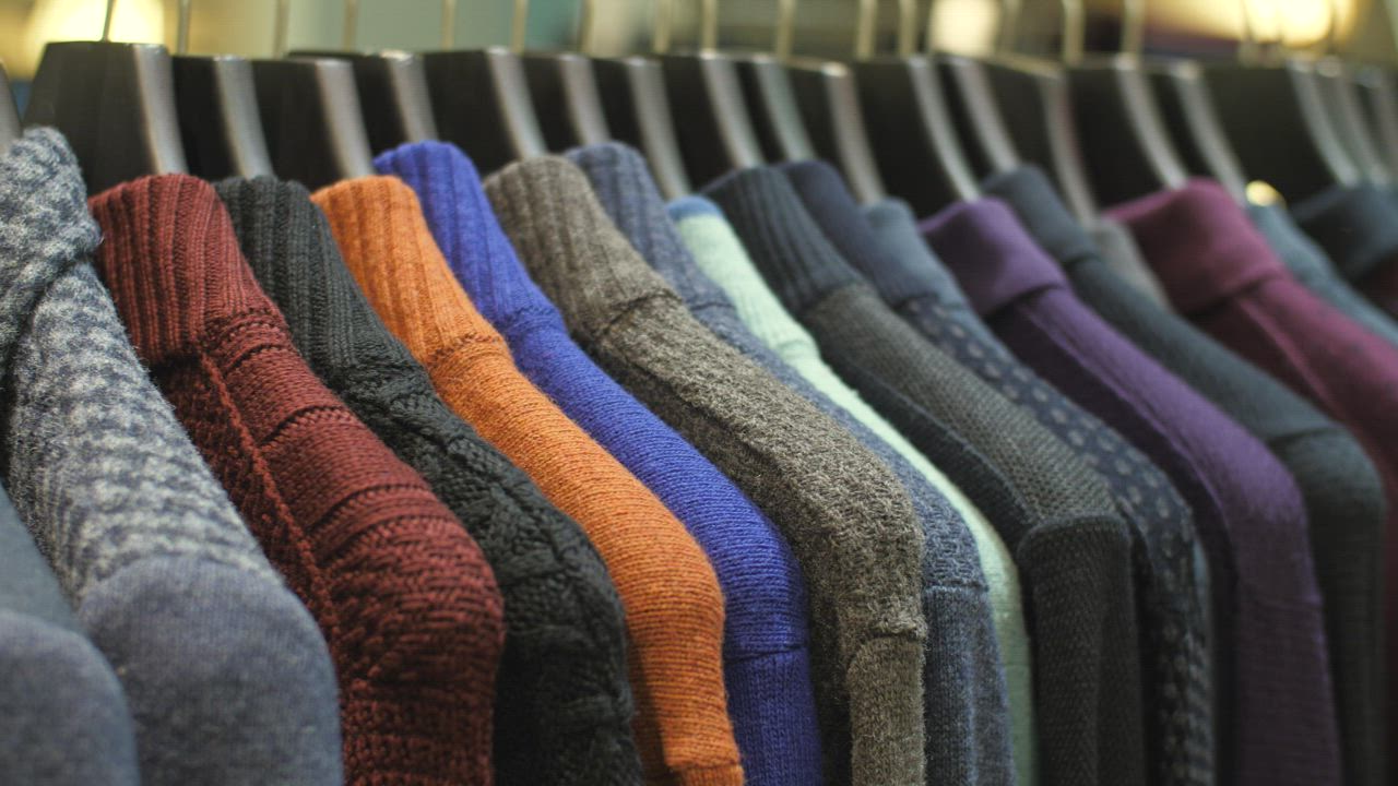 Sweaters hanging on the coat rack of a clothing store - Free Video