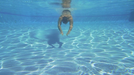 Swimming underwater in a pool.