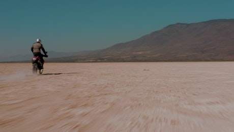 Tacking view of a motorcyclist in the desert.