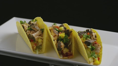 Tacos rotating on a plate on a black background
