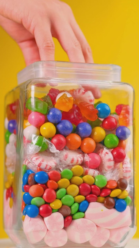 Taking candy from a pot that is on a yellow background.