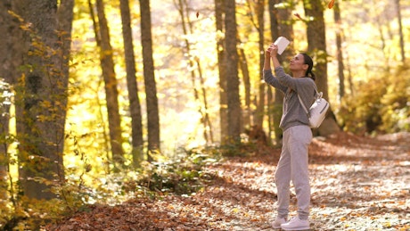Taking photos with her cell phone of autumn nature.