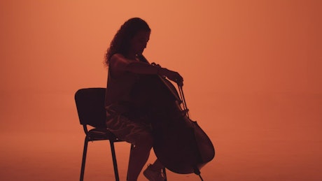 Talented cellist playing on an orange background.