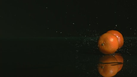 Tangerines bouncing on a black water surface.