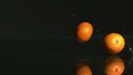 Tangerines rolling on a black surface.