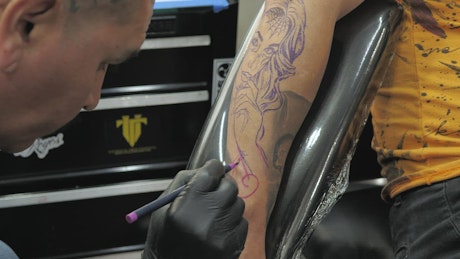 Tattoo artist drawing on the skin.