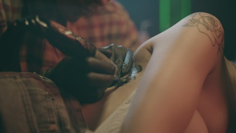 Tattoo artist making a flower over a girl.