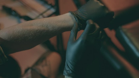 Tattoo artist puts on gloves.