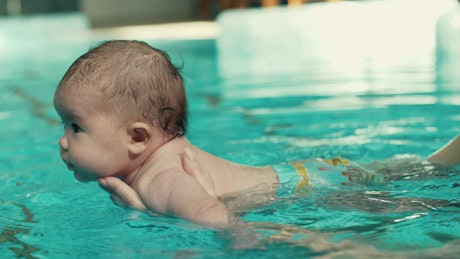 Teaching a baby to swim in the pool.