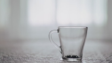 茶壶用手把茶倒进透明的玻璃杯里