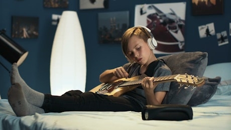 Teen boy practicing guitar on his bedroom
