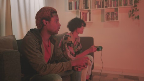 Teenage couple playing video games in the living room.