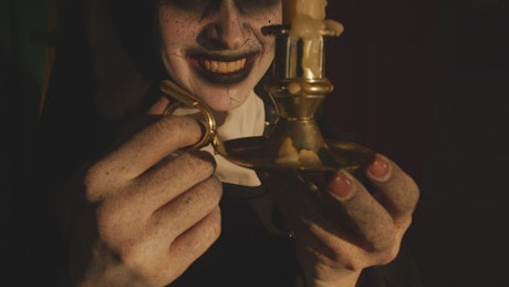 Terrifying nun looking at a candle in her hands