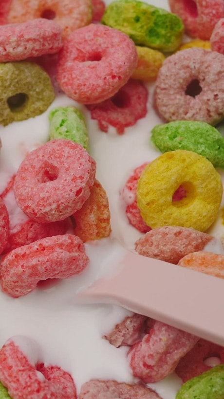 Texture of colored rings cereal with yogurt.