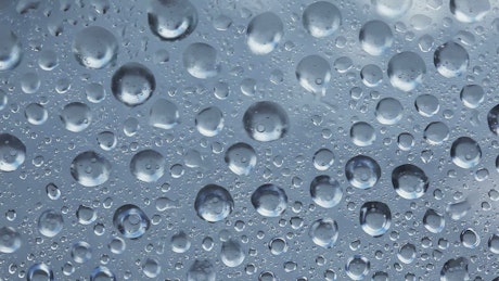 Texture of water drops vibrating on a glass.