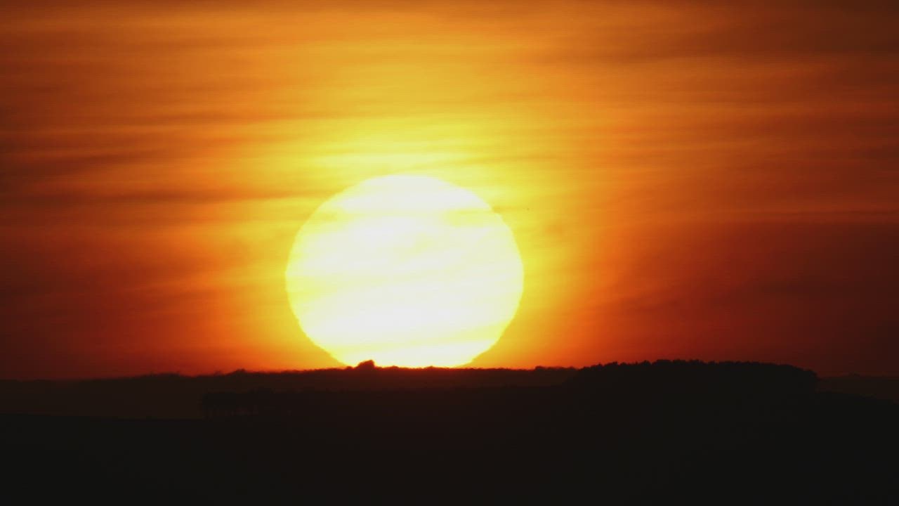 The sun hiding on the horizon during sunset - Free Stock Video