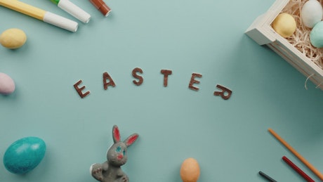 The word Easter rotating on the blue table with colorful Easter eggs.