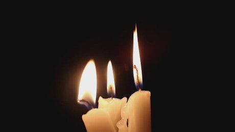 Three candles lit in the dark together.
