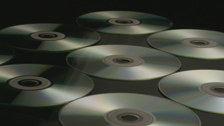 Three lines of compact discs on a black base.