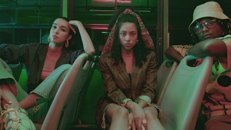 Three models posing to the lens while on board a bus.