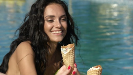 Three women enjoying an ice cream beside the pool on a hot day.