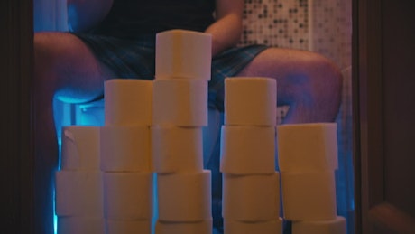 Toilet paper wall and a man sitting in the toilet.