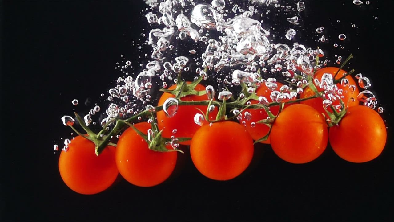 ⁣Tomatoes falling thro spaceman demo rupiah ugh water, black background