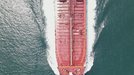 Top aerial shot of a cargo ship sailing in sea.