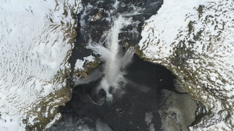 Top aerial shot of a waterfall in a winter forest.