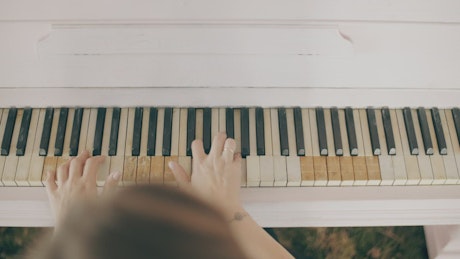 Top view of a girl playing a piano.