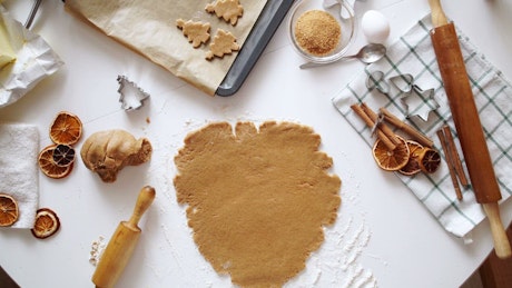 Top view of pressing cookie dough with spices and rolling pin