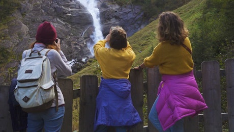 Tourists taking photos to a waterfall.