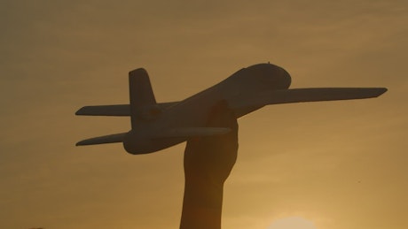 Toy plane being thrown through the air at sunset.