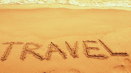 Travel written on golden sand