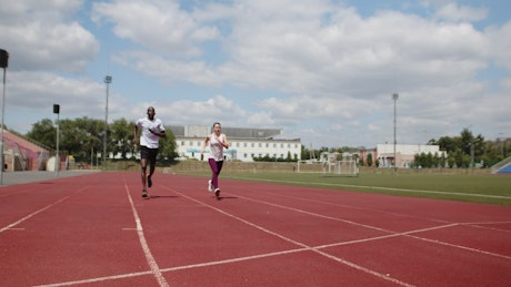 Two athletes racing a long a track share a high five.