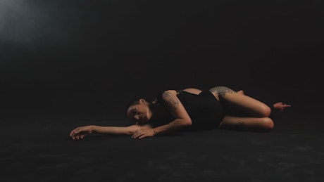 Two ballerinas lying on the floor on a black background.
