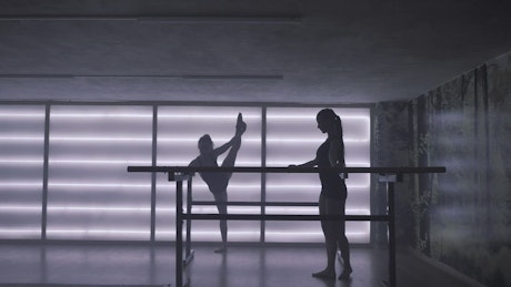 Two ballet dancers warming up at ballet salon.