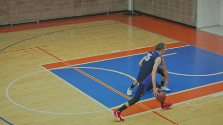 Two basketball players playing one on one.