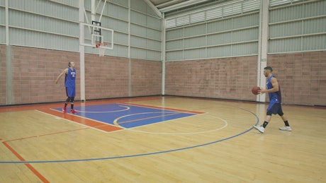 Two basketball players training on a court.