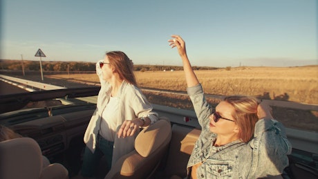 Two carefree women singing in a convertible.
