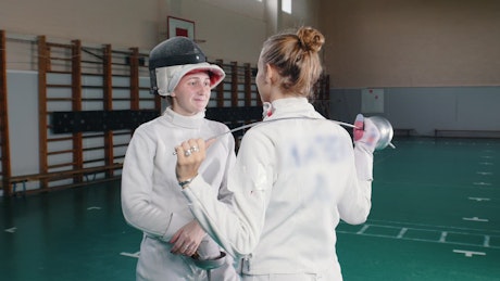 Two female fencers chatting and laughing.