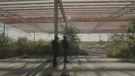 Two friends flying a drone outdoors in an abandoned place.