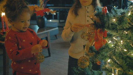 Two girls adorning a festive tree for Christmas.