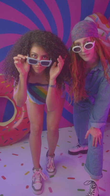 Two girls dancing in a colorful spot.