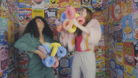 Two girls playing with giant cereal