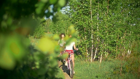 Two girls riding bikes in nature.