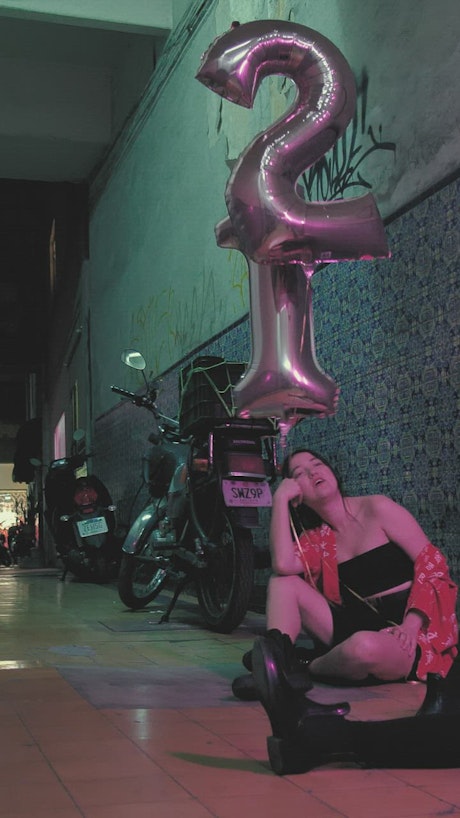 Two girls with balloons sitting while talking.