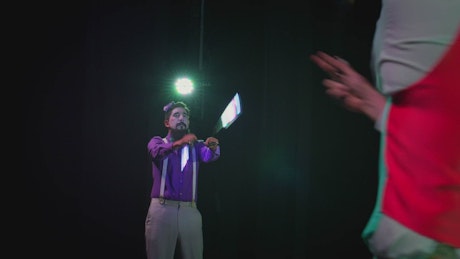Two jugglers performing on a stage.