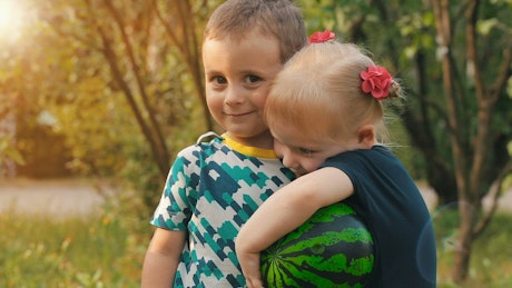 Two little boy and girl hugging in nature.