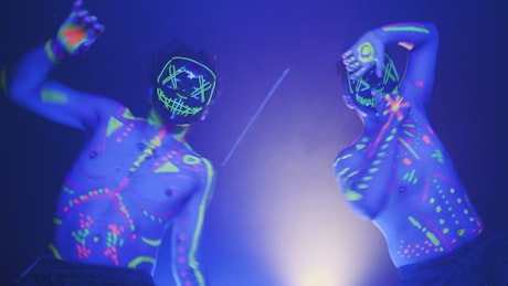 Two man with masks dancing with party light.